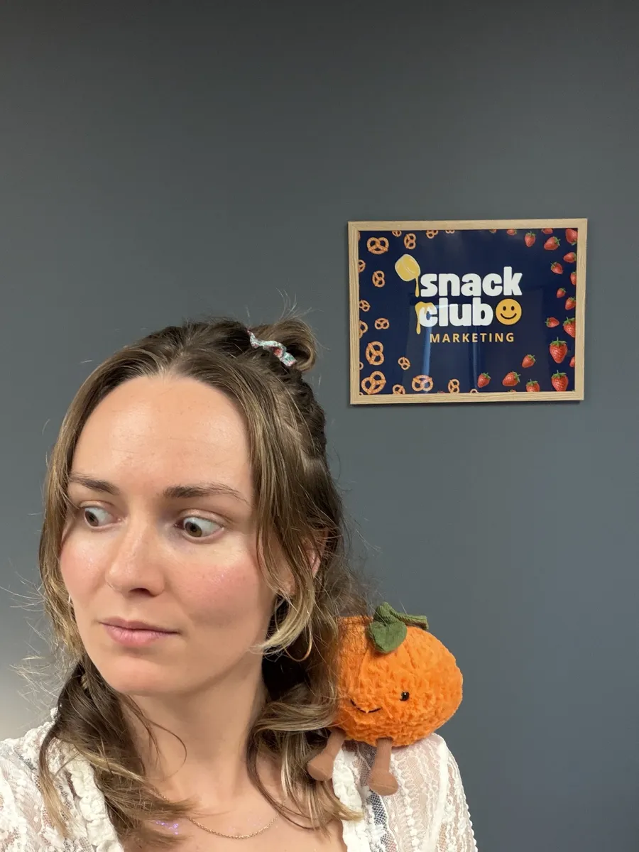 Bre looking down at the plush orange on her shoulder
